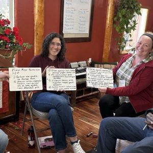 Participants at Biduum Coloratanum smile as they show off Latin exercises written on small white boards